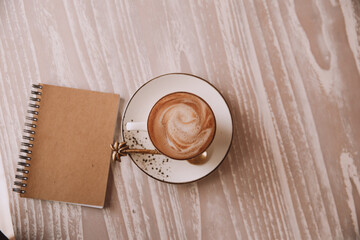 white cup of hot cappuccino on wooden light table background.