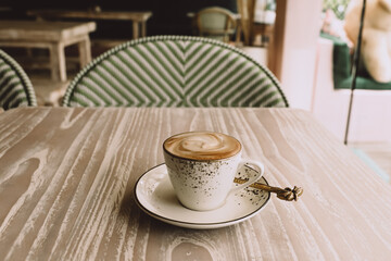 white cup of hot cappuccino on wooden light table background.