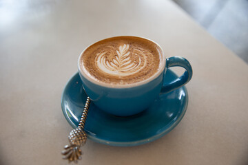 Cup of tasty cappuccino with latte art on wooden table background.
