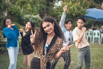 A young asian woman with four of her colleagues have a great time outdoors. Workmates unwinding and posing for the camera. Party scene.