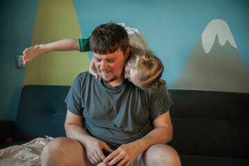 daughter plays with dad, crawling over him, climbing onto his neck at home