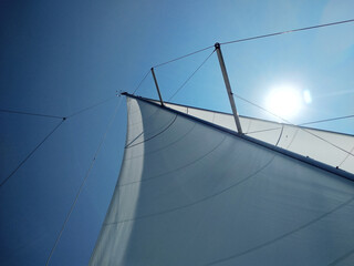 Fototapeta premium Bright sun over the sail on a background of blue sky