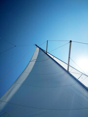 View of the bright sun over the yacht's sail on a clear summer day