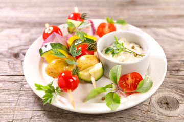 vegetable skewer and dipping sauce on plate