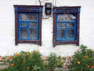 Old rural Ukrainian house. White Wall with blue windows.