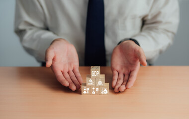 GDP, symbol of gross domestic product Businessman holding a wooden block with an icon saying 'GDP' copy space. Business and GDP growth. Gross domestic product concept.