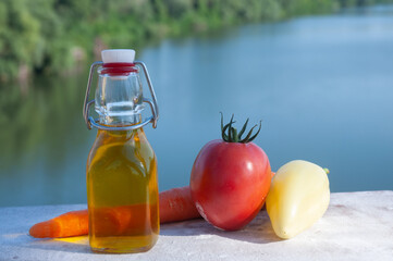 Vegetables and olive oil are on the board over the river.