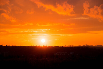 Banner. Beautiful red-orange fiery sunset over the city. Dark clouds in the sky. The outlines of...