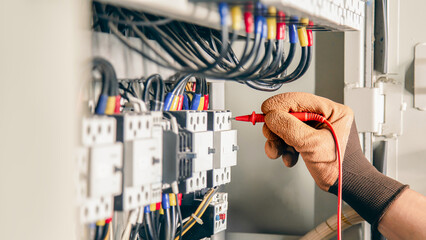Electrical engineer checking the operation of electrical control cabinet, maintenance concept.