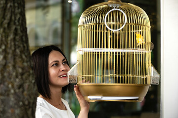young beautiful brunette woman in a bar admiring a canary bird in a golden cage