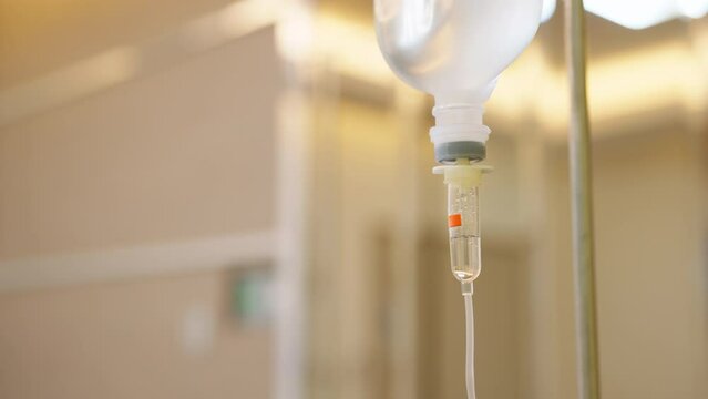 Close up saline solution IV drip fluid intravenous Drop Saline Drip for patient in hospital with blur ward room. Health care and medical concept. Treatment emergency and injection drug infusion care