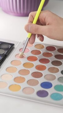 Close-up view of a makeup artist taking eyeshadows with makeup brush from professional eyeshadow palette. Make-up and beauty concept.