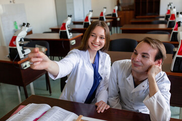 Obraz premium High School Students Looking Through Microscope In Biology Class. Young scientist doing some research
