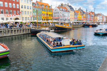 Fototapeta na wymiar Nyhavn is a sightseeing and entertainment district with its canal and colorful houses and old ships. Tourists taking a canal tour with a sightseeing boat. 19 July 2022 Copenhagen, Denmark 