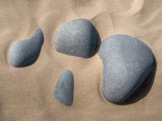 Fototapeta na wymiar Grey pebbles on golden sandy beach, abstract effect image.