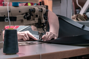 The seamstress sews on an old sewing machine, threads the fabric. Women's hands