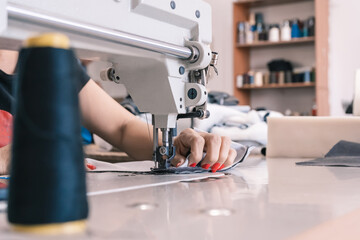 The seamstress sews at the sewing machine, threads the fabric. Women's hands