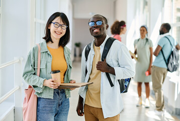Portrait of multiethnic couple of students smiling at camera standing together at school corridor