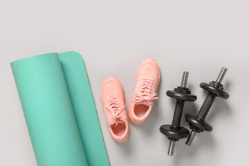 Sport and fitness equipment, female pink shoes, yoga mat on grey background. Copy space. View from...