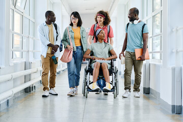 African girl in wheelchair chatting with her friends while they walking along the school corridor