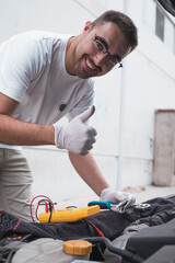 Mecánico sonriente ante la cámara feliz de arreglar un coche. Mecánico en su taller arreglando...