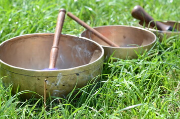 Tibetan singing bowls with sticks on the grass - music instruments for meditation, relaxation after yoga practice and healing massage