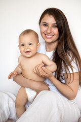 A portrait of a beautiful young mother and her sweet baby in a diaper. Motherhood. Happy family