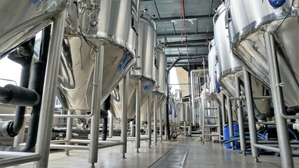 Row of shiny metal micro brewery tanks or Fermentation mash vats in Brewery factory.