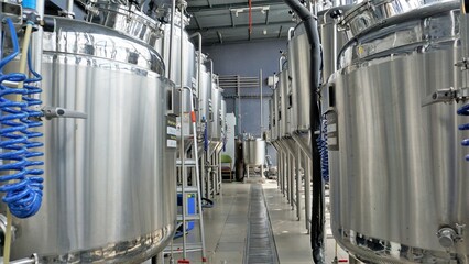 Row of shiny metal micro brewery tanks or Fermentation mash vats in Brewery factory.