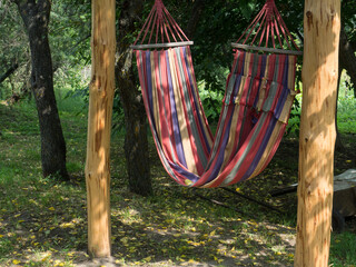 red and blue striped hammock hanging in a grassy backyard