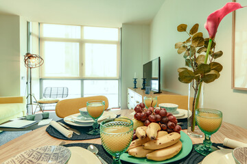 Apartment decorated in pastel colors with a breakfast table with assorted fruit and juices in crystal glasses
