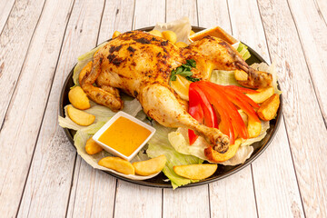 Charcoal grilled chicken with potato wedges, sauces, lettuce, parsley, lemon slices and fresh red pepper