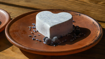 Homemade lavender ice cream in in the shape of a heart in rural clay plate decoration blueberry. Creamy vegan lavender ice cream.