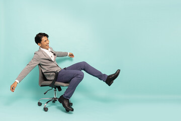 Asian businessman sitting on office chair and feeling happiness isolated on green background, Excited businessman winner success concept