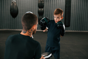 Practicing together. Coach is teaching the boy box techniques indoors