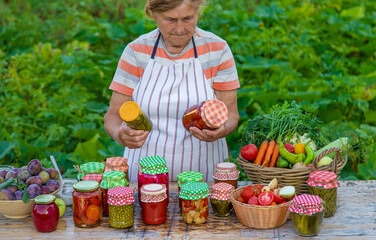 Senior woman preserving vegetables in jars. Selective focus.