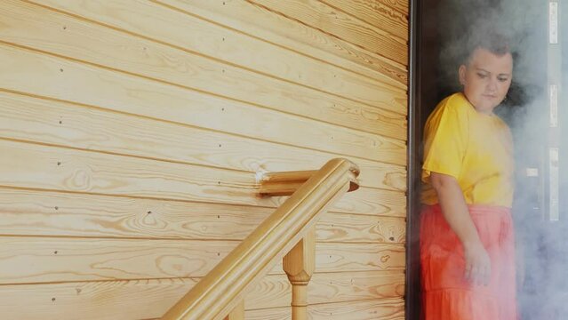 A woman with a Mohawk hurriedly leaves the smoky house going down the stairs. Medium plan