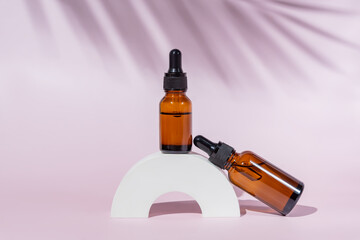 mockup of dark glass pipette dropper bottles for branding of medicine or cosmetics - beauty oil, essence oil or serum. Cosmetic bottle container on a pastel pink background. Minimalism.