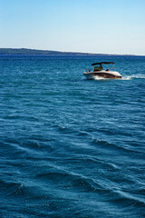 fast tourist boat rushes and leaves a white wake on the slightly agitated Adriatic sea, Croatia, summer, afternoon