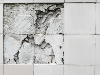 A wall with a broken off gray tile from the wall
