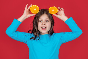 surprised teen kid holding orange fruit on purple background