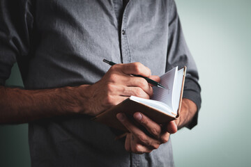 businessman holds a pen and notebook and writes down