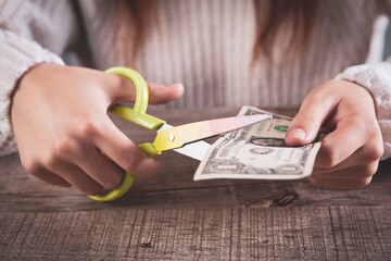 young woman cuts money with scissors