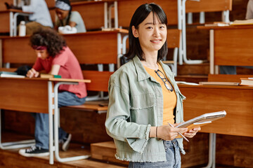 Portrait of Asian student with books smiling at camera visiting lecture at university