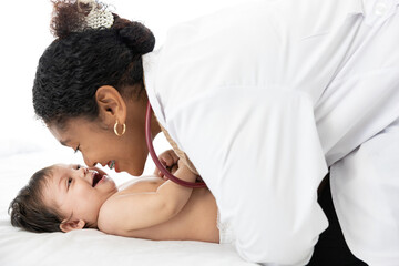African doctor pediatrician examining and kissing baby on the bed