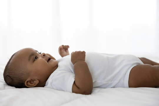cute African baby lying on bed at home