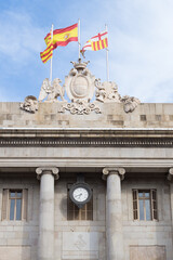 Flags of Catalonia, Spain and Barcelona flying over Barcelona City Hall. Neoclassical and gothic façade with Barcelona City Council in Catalan.