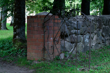 Fototapeta premium an outdoor park with green grass and an ancient building in the distance at an open iron gate in sunny weather