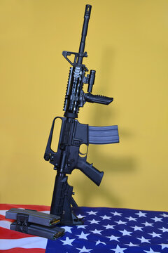 An American-made automatic carbine rifle standing over the US flag.  A concept image for gun control, home security, personal protection, and the US military power.