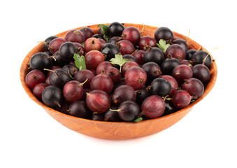Bowl full of ripe red gooseberries from the new crop over a white background.